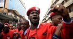 Bobi Wine Plans To Run For President In 2021 31 Bobi Wine, dressed in a red jacket and cap, shakes his fist in front.